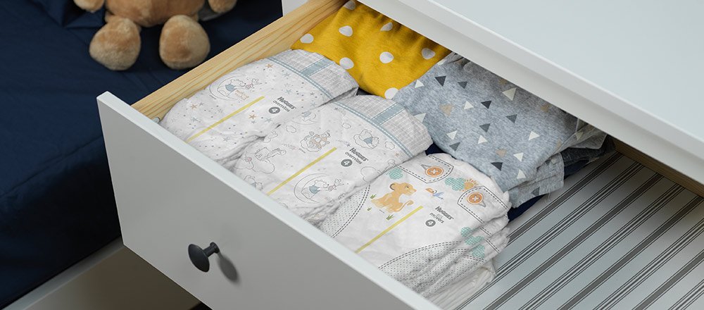 The top drawer of a white dresser is pulled out to display multiple Huggies Overnites Diapers with wetness indicators