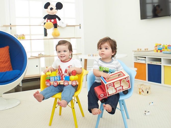 toddler siblings sitting in chairs playing