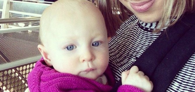 Baby with big blue eyes being held by mom