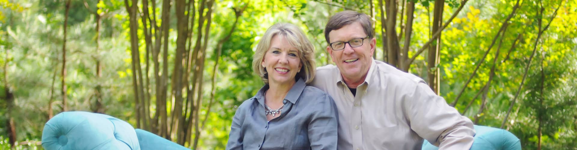 Dennis and Barbara Rainey Dennis and Barbara Rainey smiling, sitting on a couch in the woods.