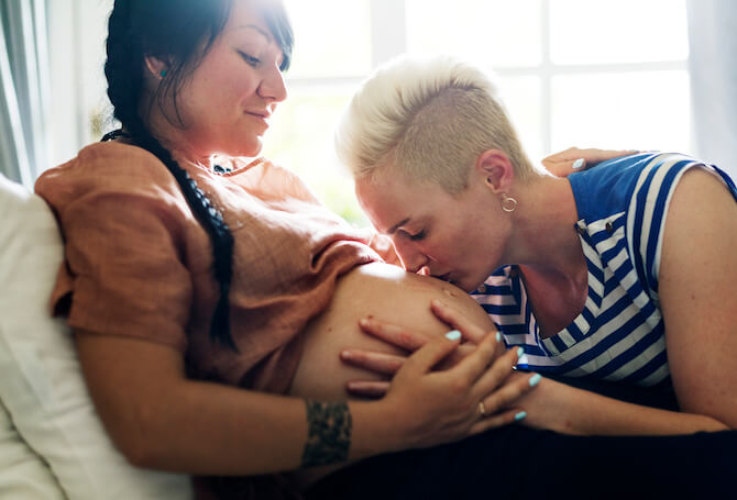 Mothers embracing pregnancy belly on bed