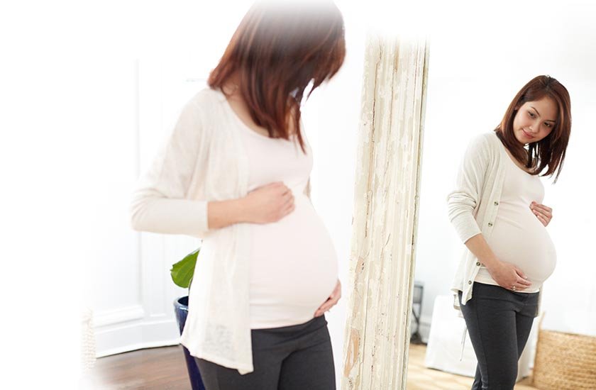 Pregnant mom admiring her belly in the mirror​
