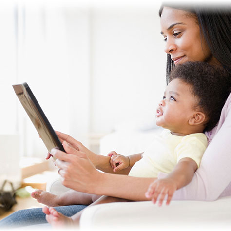 Mom typing on tablet while holding baby