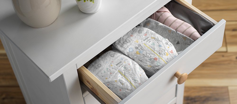 The top drawer of white dresser is pulled out to display multiple Huggies Little Movers Plus Diapers with Disney Designs