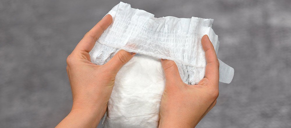 Hands holding a Huggies Little Movers Plus Diaper demonstrating its flexibility