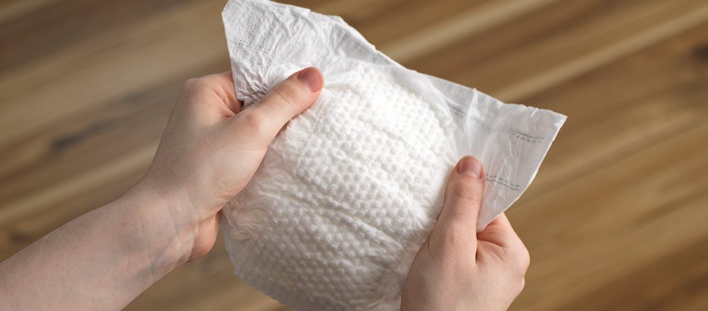 Hands holding a Huggies Little Snugglers Diaper showing the Gentle Absorb liner