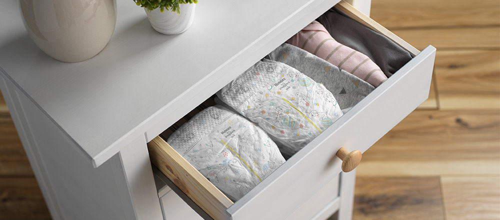 The top drawer of white dresser is pulled out to display multiple Huggies Little Snugglers Plus Diapers with Disney Designs