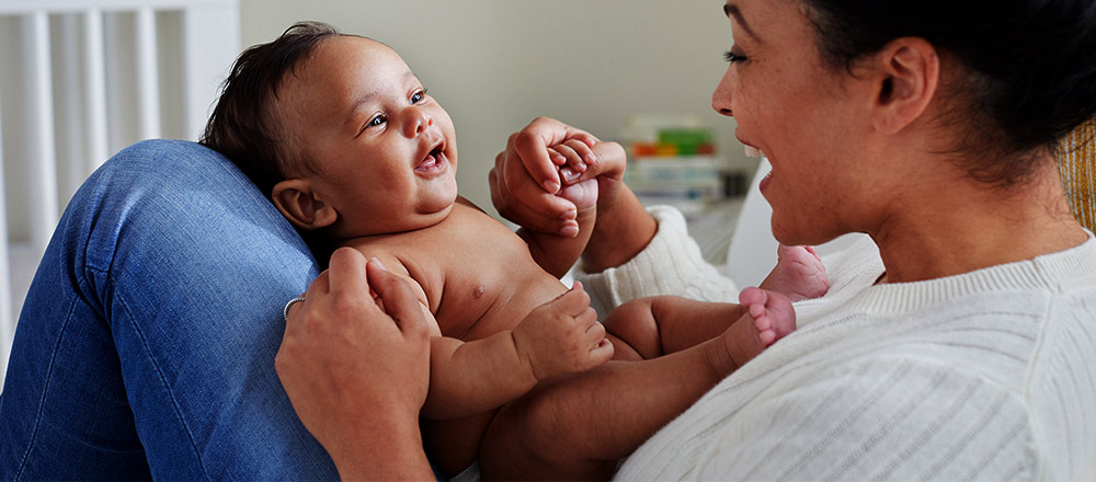 A laughing mother holding a baby on her lap