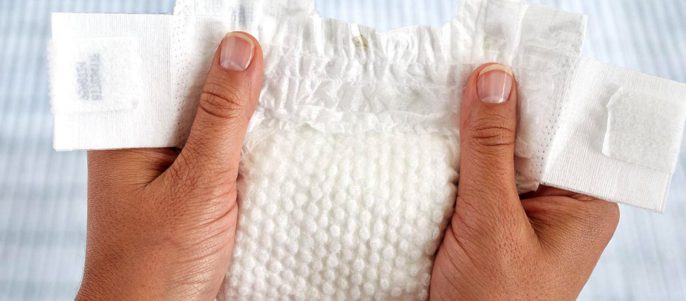 Hands holding a Huggies Little Snugglers Plus Diaper showing the Gentle Absorb Liner
