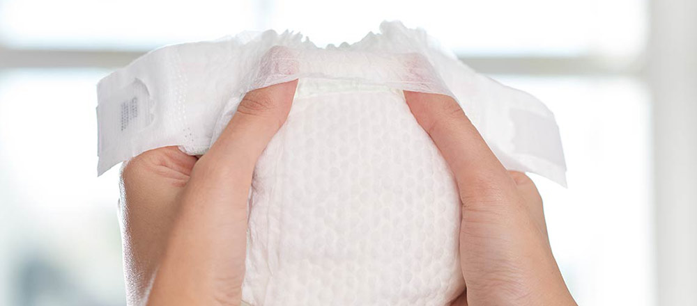 Hands holding a Huggies Little Snugglers Plus Diaper demonstrating its Pocketed Waistband