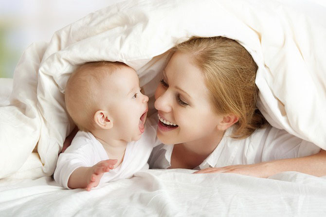 Mom playing with baby under blanket