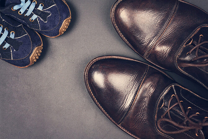 Overhead shot of brown dress shoes across from child velcro shoes
